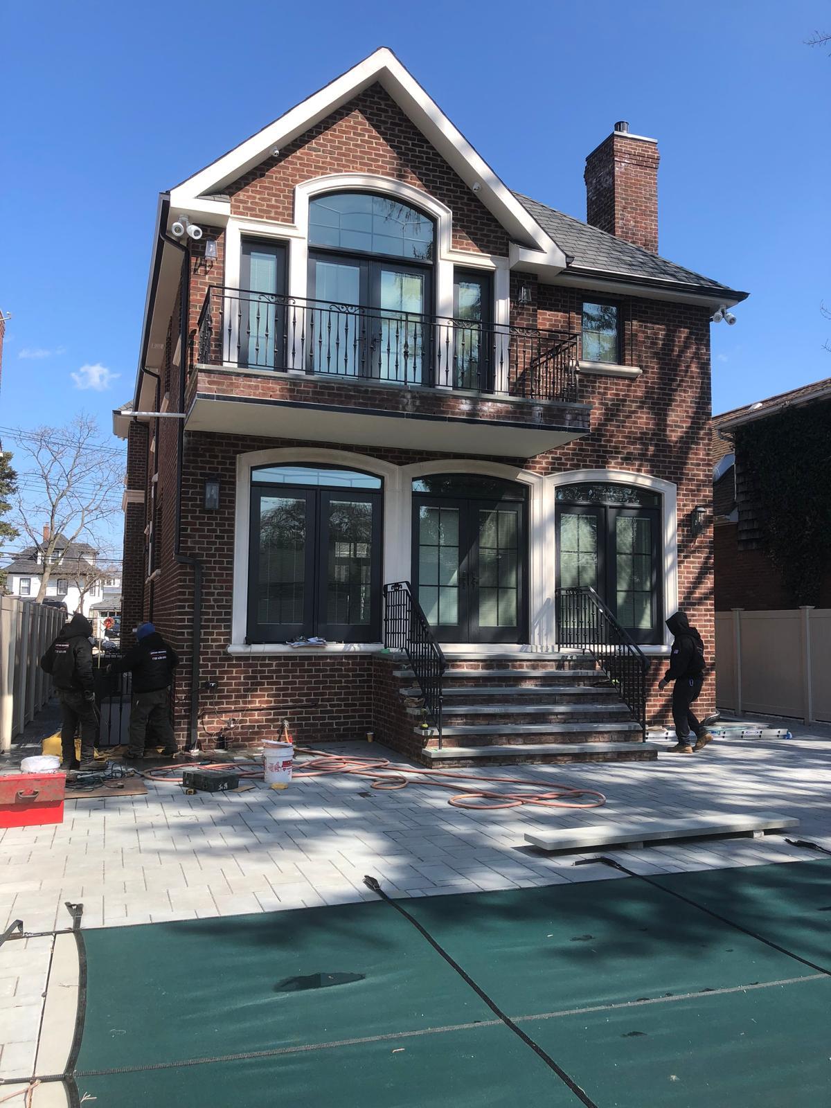 Custom brick home with balcony, arched windows, and stone patio