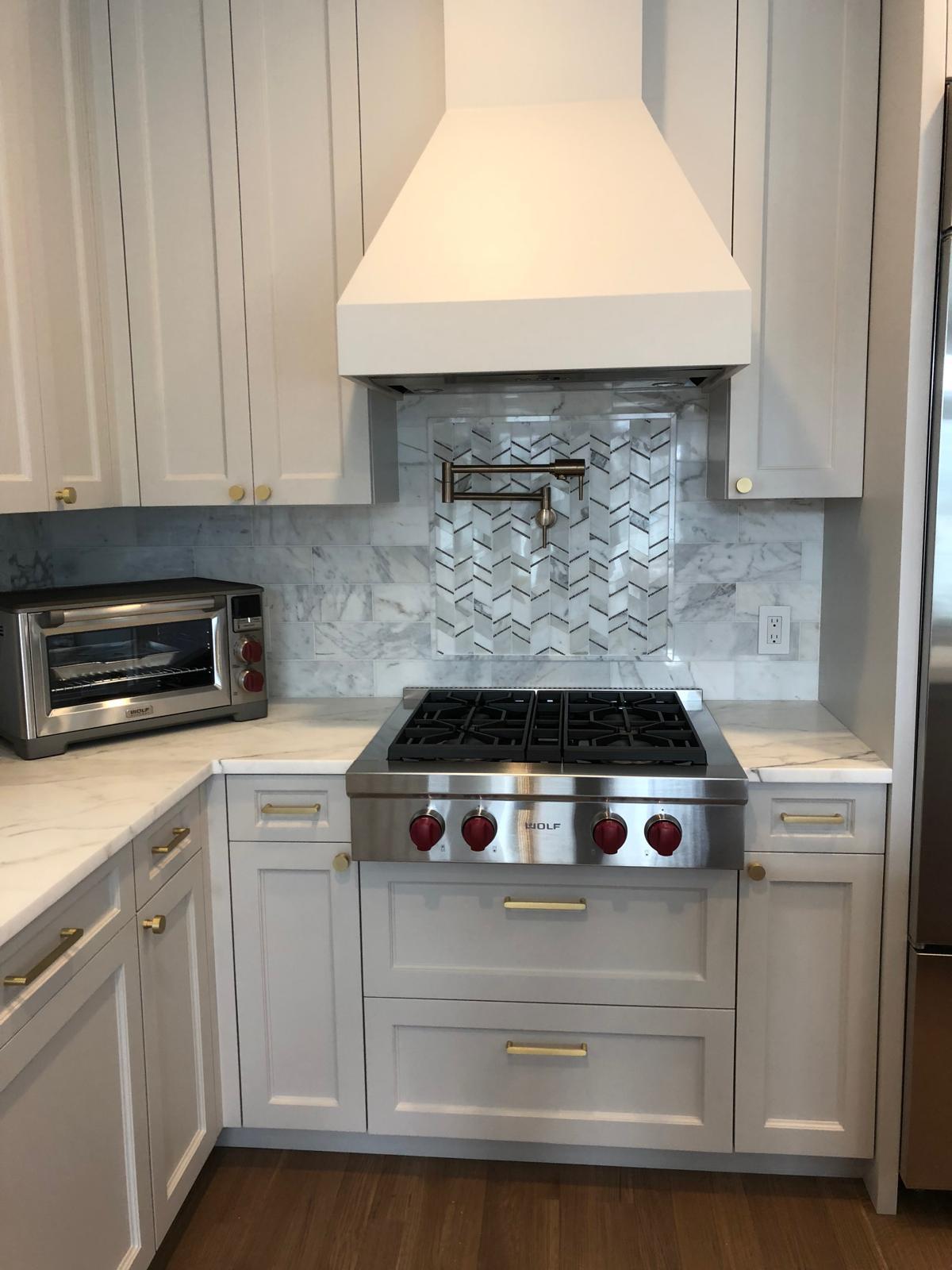 Wolf range with custom hood and marble backsplash