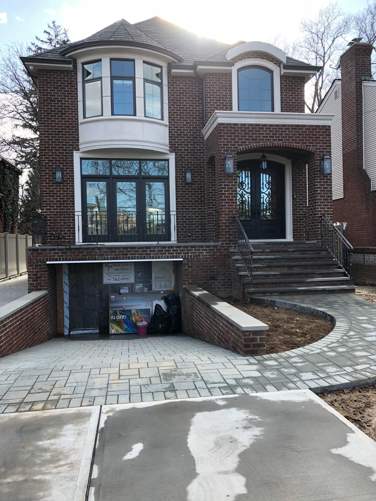 Custom brick townhouse with bay windows, wrought-iron entry doors, and paver driveway